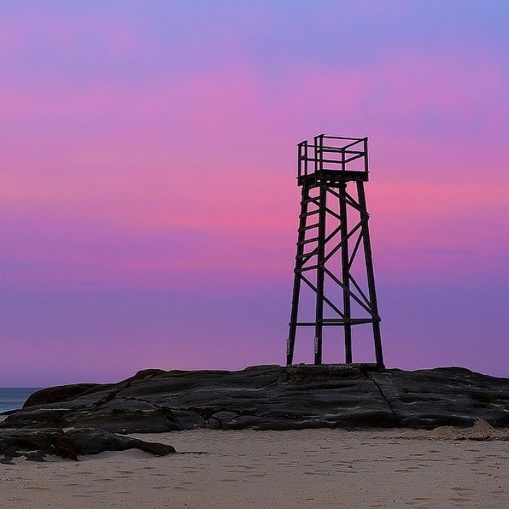 A shark watchtower with a sunset behind it
