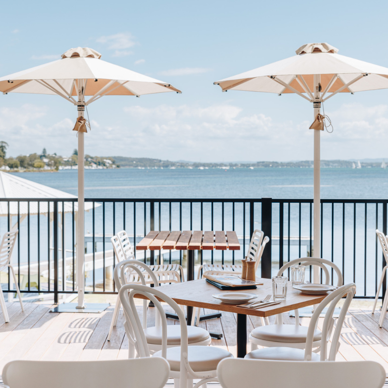 Two tables and umbrellas at a restaurant overlooking Lake Macquarie